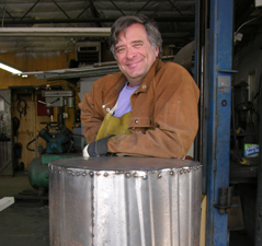 Sculptor Kevin Caron leaning on the shipping case for the sculpture Charmed